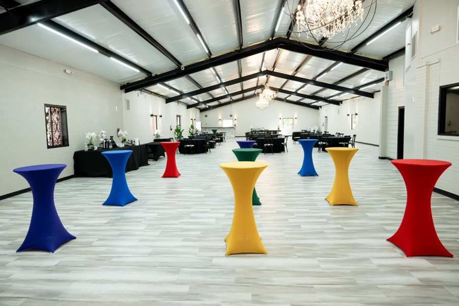 Inspira Ranch event hall interior with vaulted ceiling, chandelier, and cocktail tables