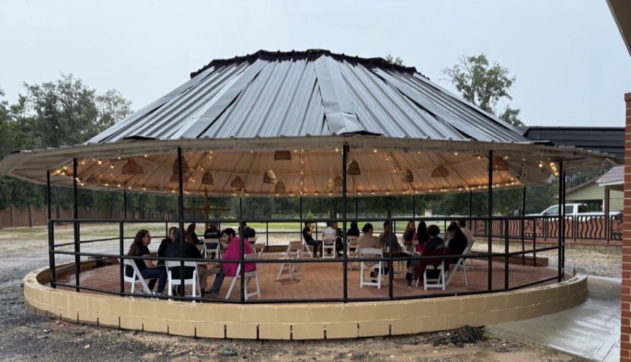 Inspira Ranch round outdoor pavilion with guests seated under rattan pendant lights