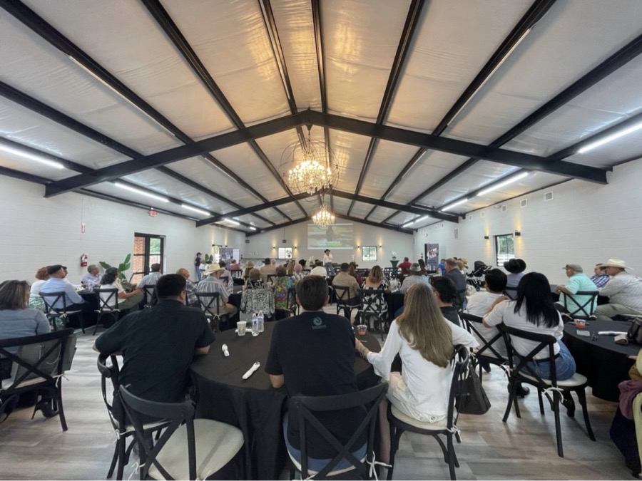 Inspira Ranch Salón — full hall view with guests seated at black round tables